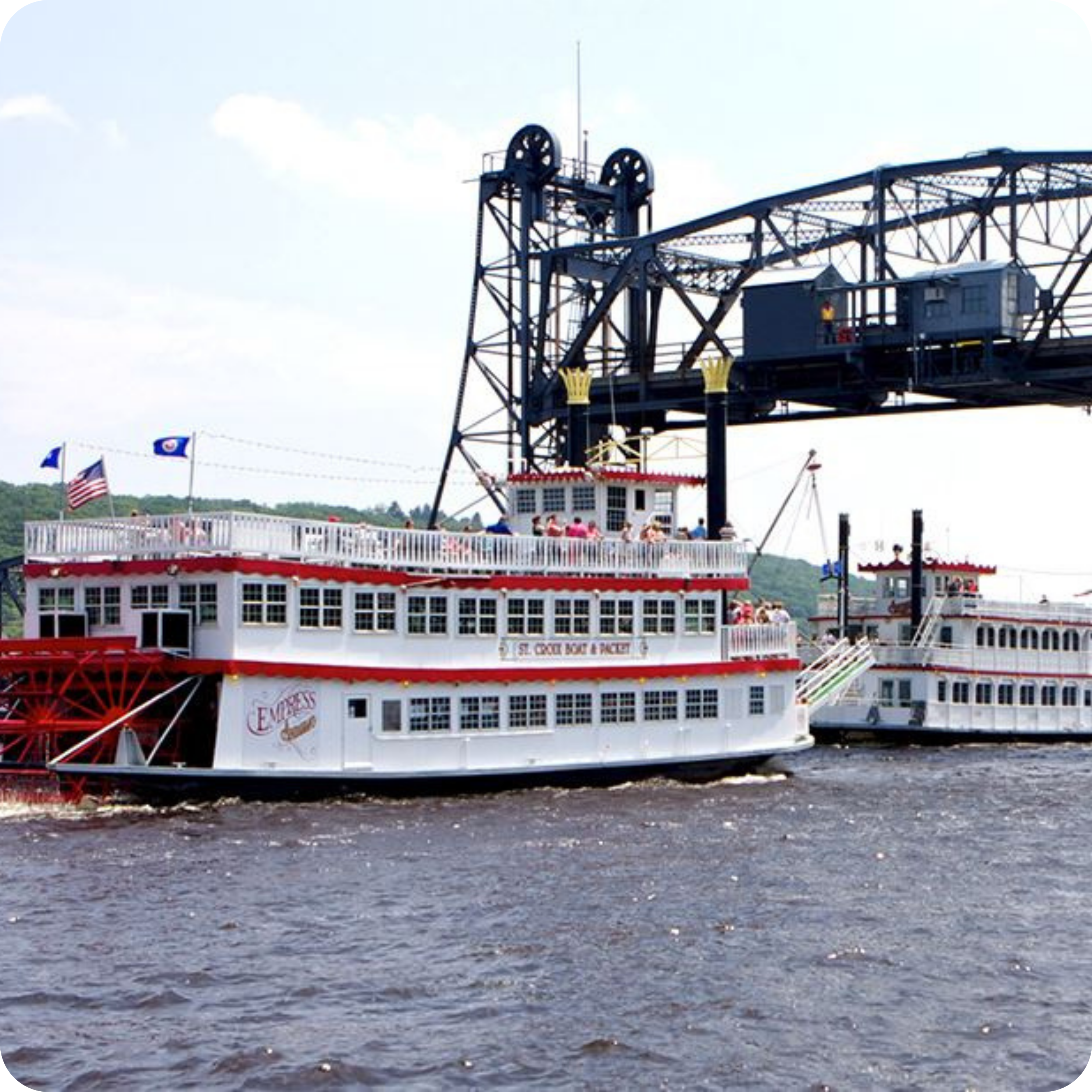Two riverboats on the St. Croix River in Stillwater, Minnesota, with a large lift bridge overhead.